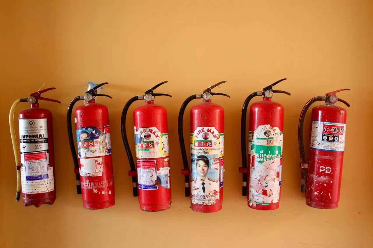 Row of red fire extinguishers mounted on an orange wall